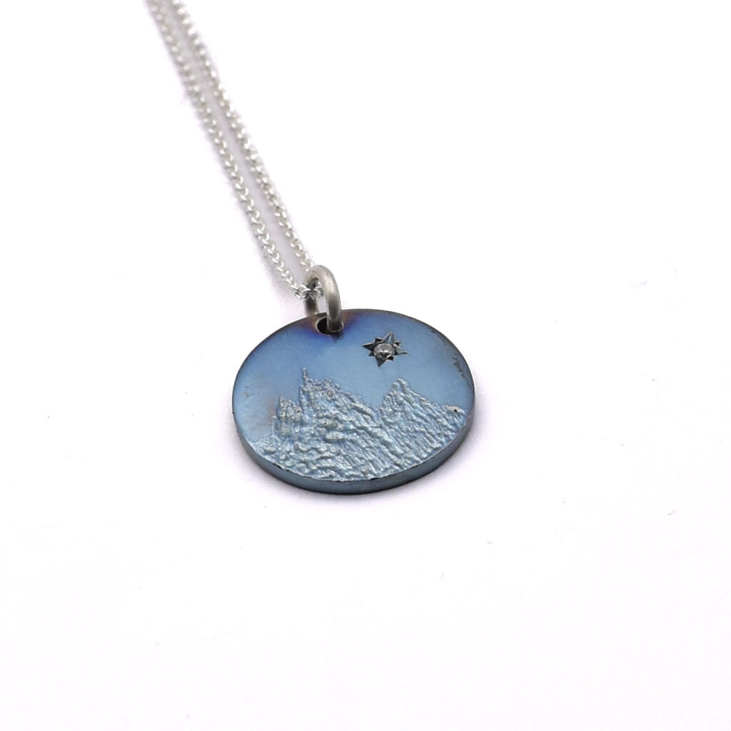 Antoine Puygrenier artisan bijoutier joaillier Lyon médaille naissance en zirconium gravée main personnalisé unique lettre prénom paysage montagne bleu