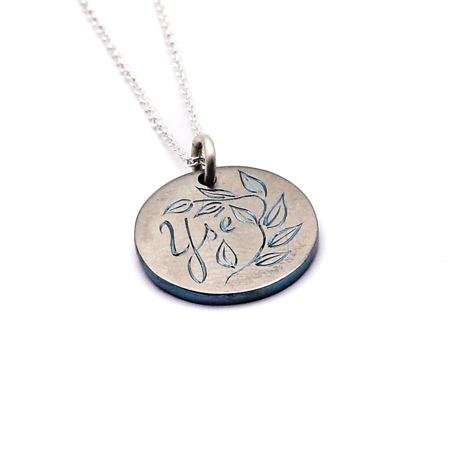 Antoine Puygrenier artisan bijoutier joaillier Lyon médaille naissance en zirconium gravée main personnalisé unique lettre prénom bleu